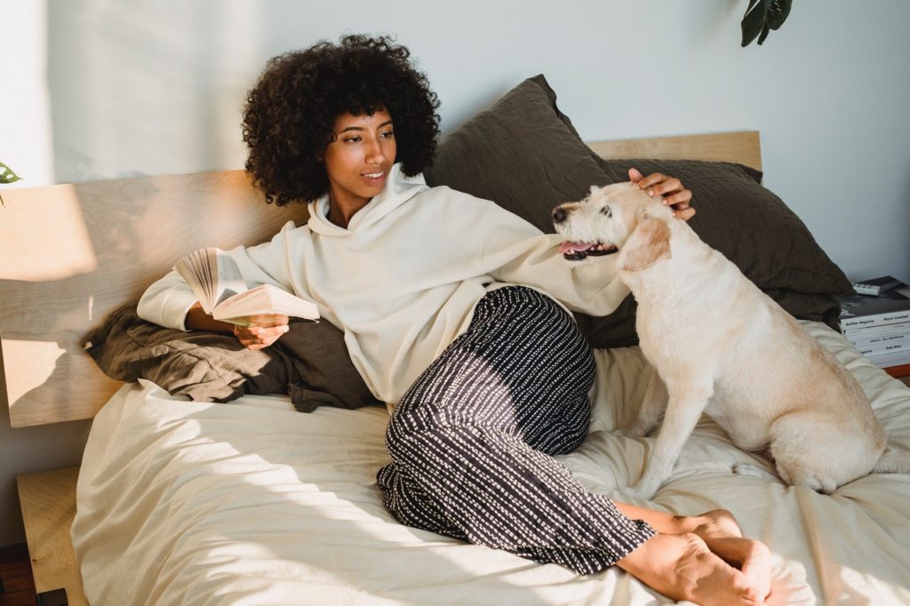 woman in bed next to her dog