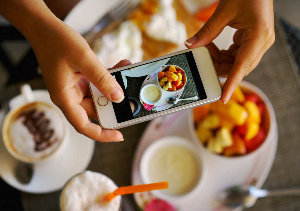 a woman using phone camera to capture unique dish