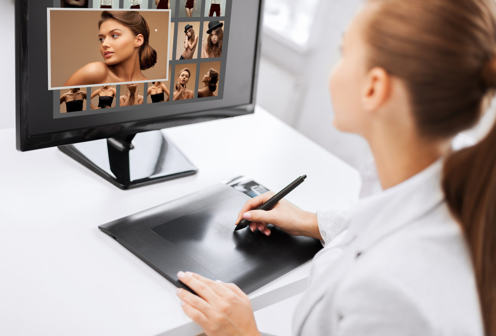 a young woman using a computer and tablet to edit photo