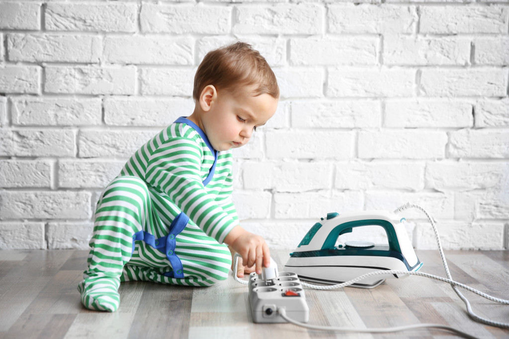 child playing with iron and electric power bar at home