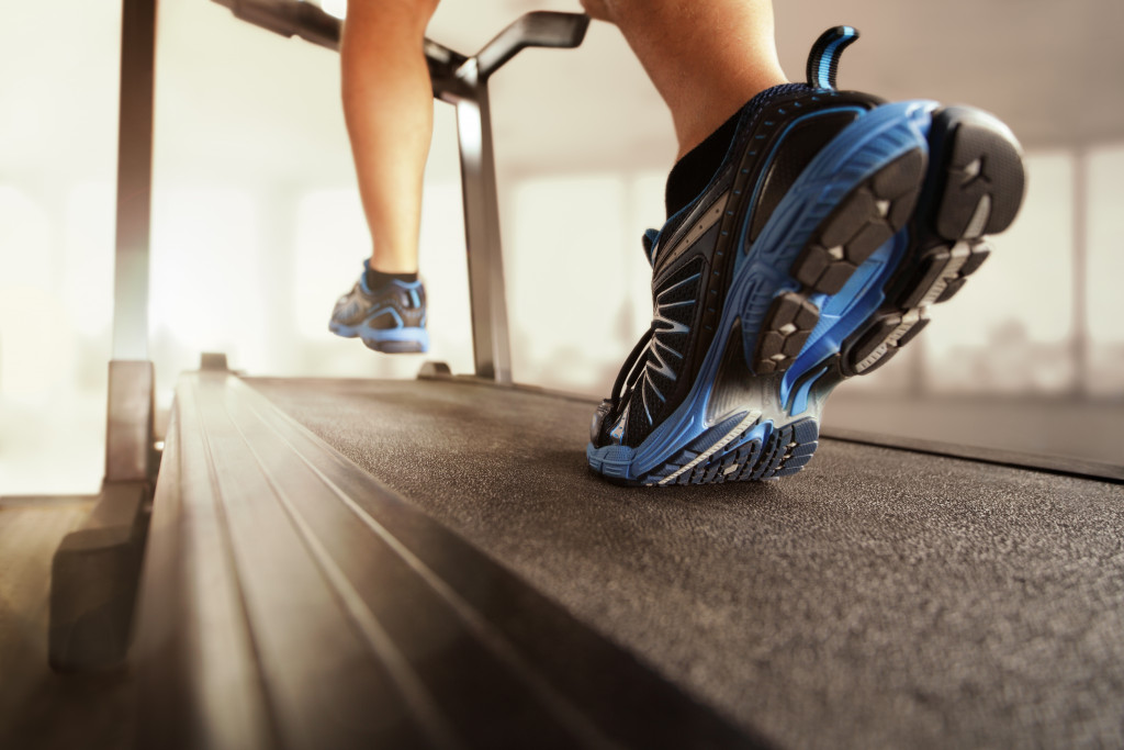 person running in treadmill with blue and black running shoes