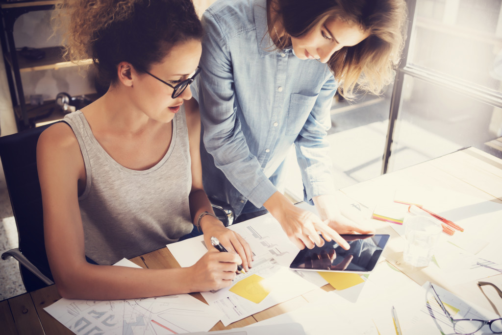 2 women looking at a tablet while working